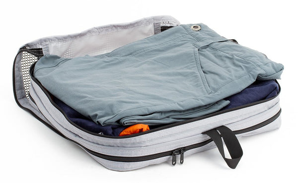 A set of clothes folded in a Northwest Sky (light grey) Aether Large Laundry Aeronaut 30 Packing Cube.